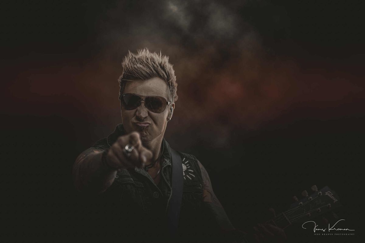 Nicki Jack på scenen med guitaren, peger mod publikum